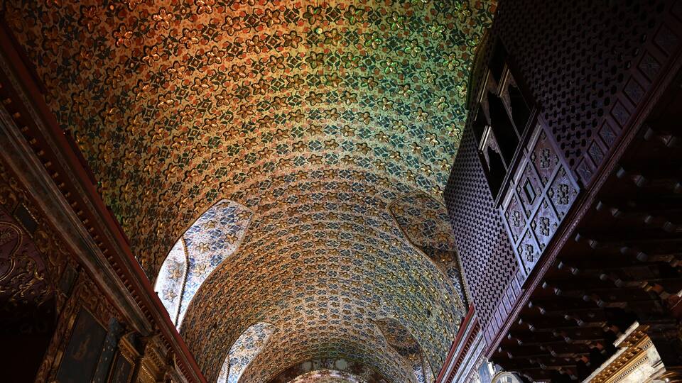 A detailed ceiling with intricate mosaic patterns and wooden architectural elements.