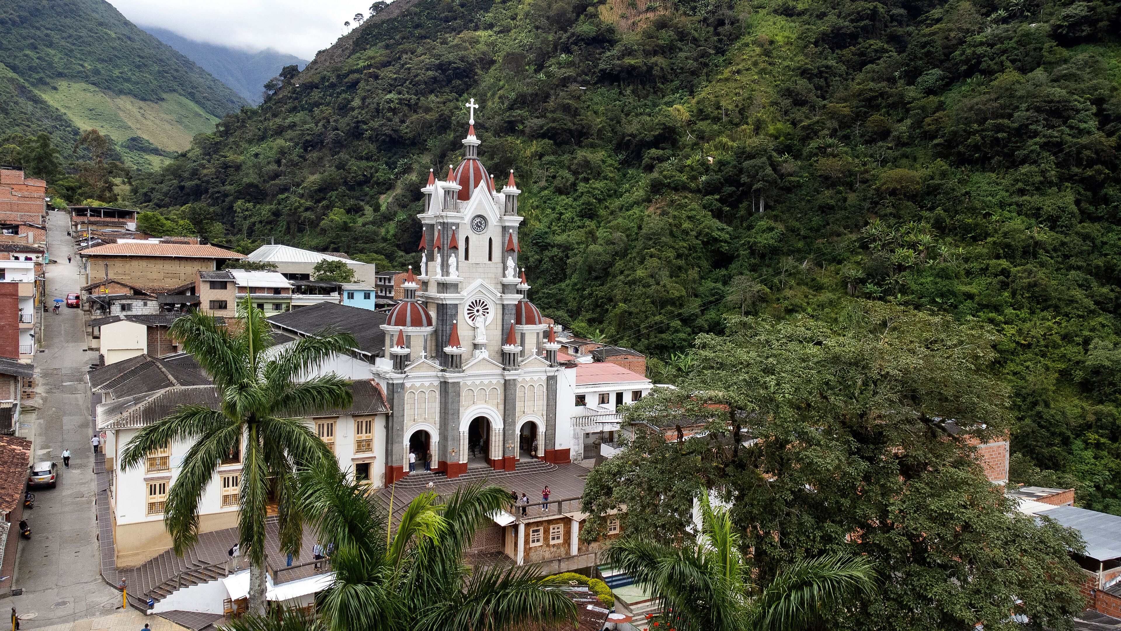 A church with a clock tower surrounded by lush greenery and residential buildings.