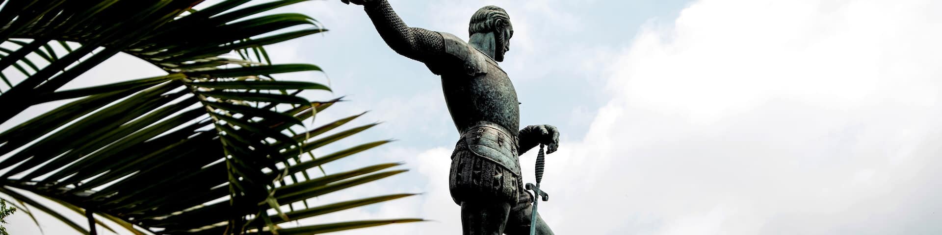 Statue of Sebastián de Belalcázar at the top of a viewpoint, with a panoramic view of the city of Cali, Colombia. He points with his right hand towards the horizon.