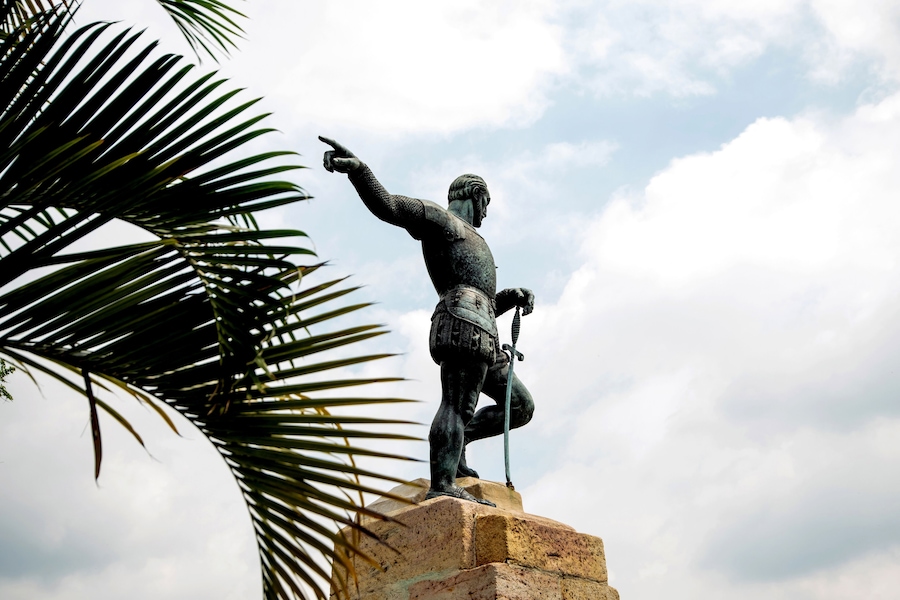 Statue of Sebastián de Belalcázar at the top of a viewpoint, with a panoramic view of the city of Cali, Colombia. He points with his right hand towards the horizon.