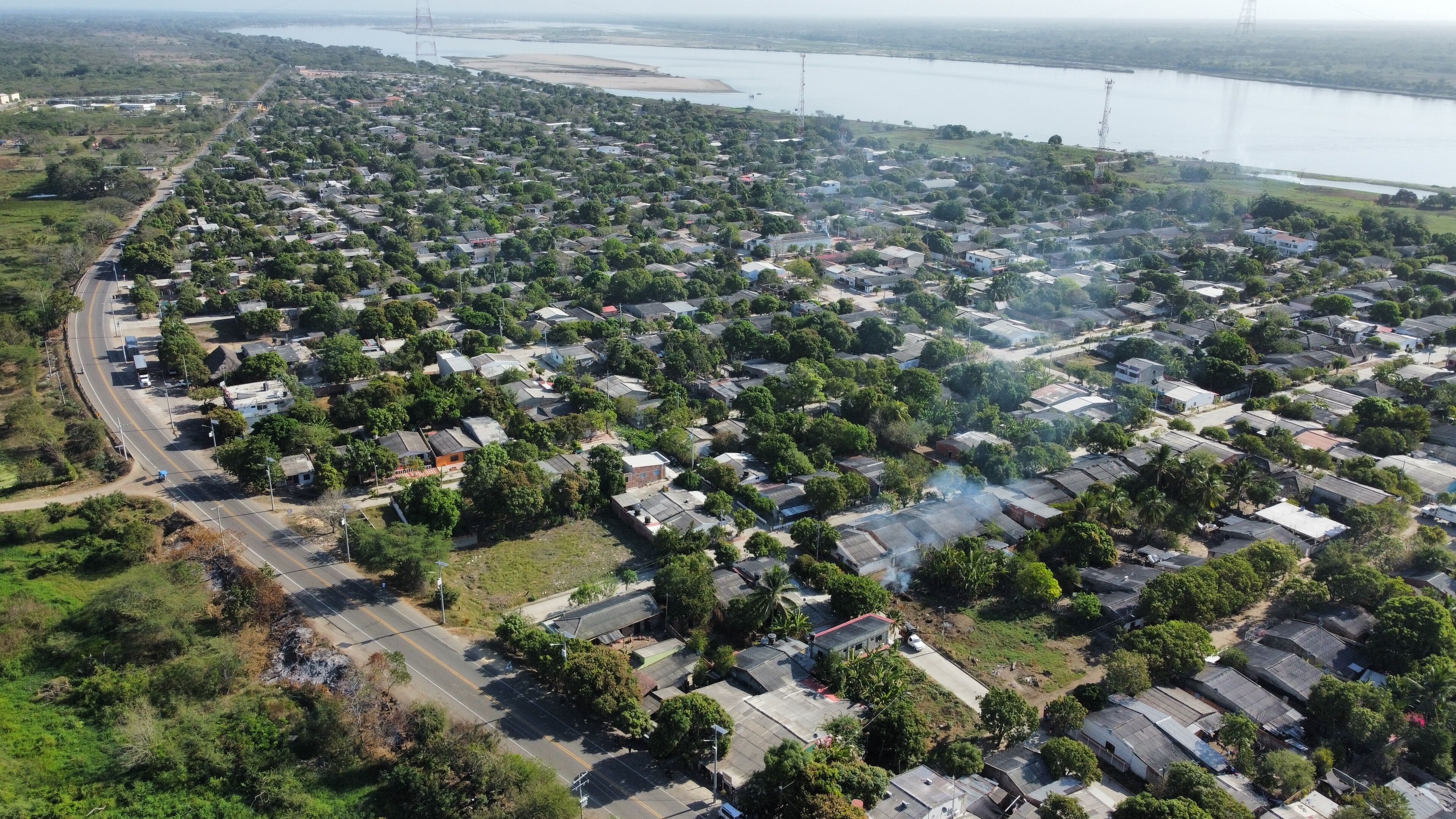 An aerial view of a residential area with houses, roads, and a body of water in the background.