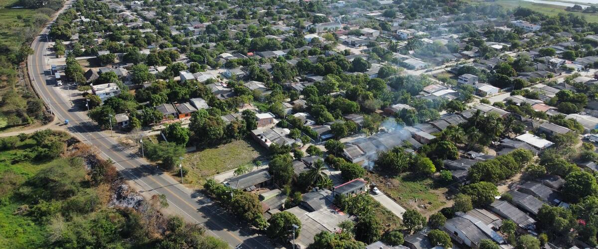 An aerial view of a residential area with houses, roads, and a body of water in the background.