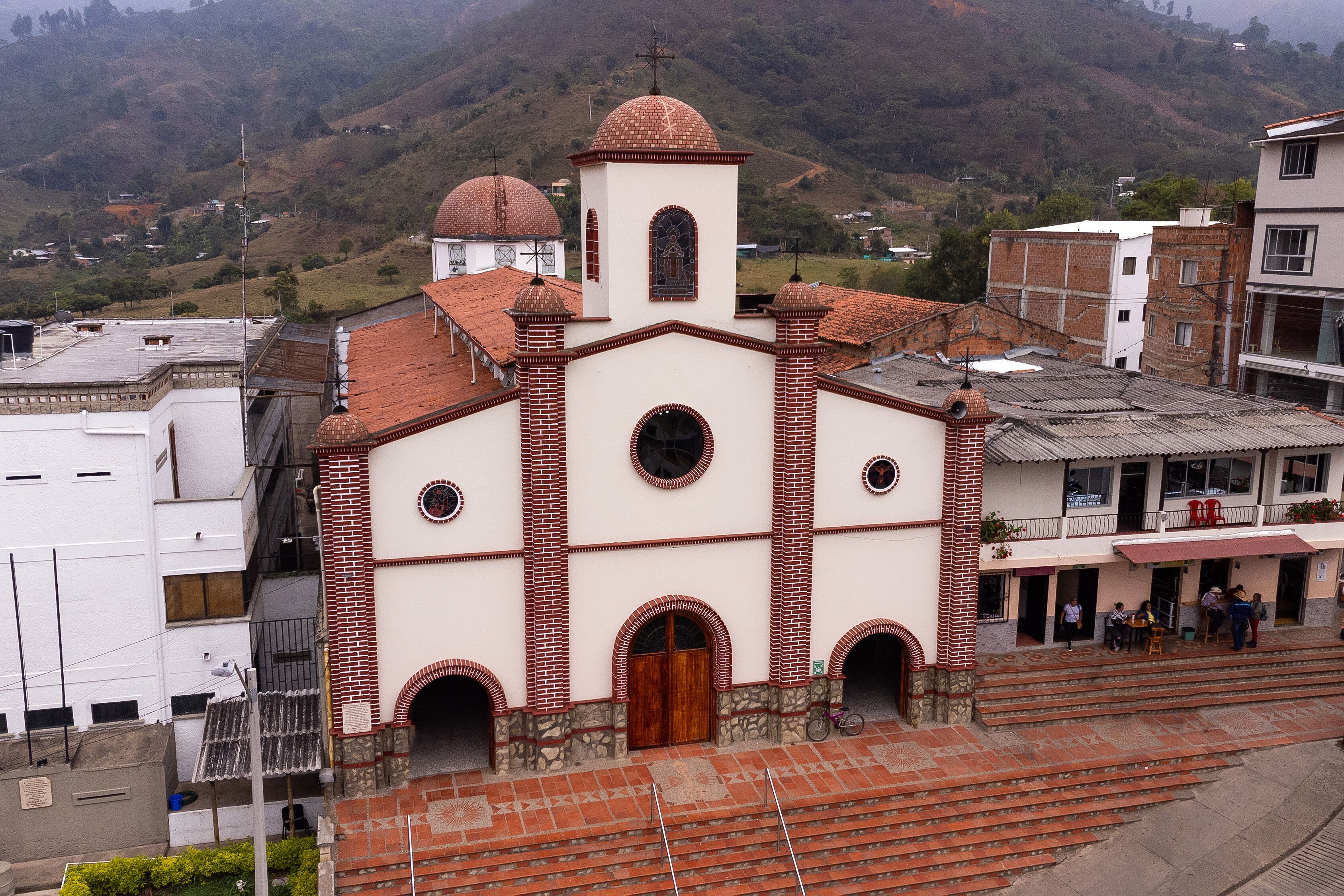 A church with a dome and bell tower, surrounded by buildings and hills.