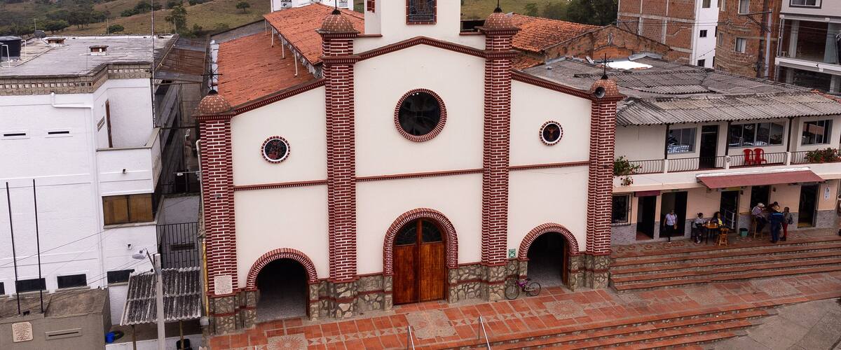 A church with a dome and bell tower, surrounded by buildings and hills.
