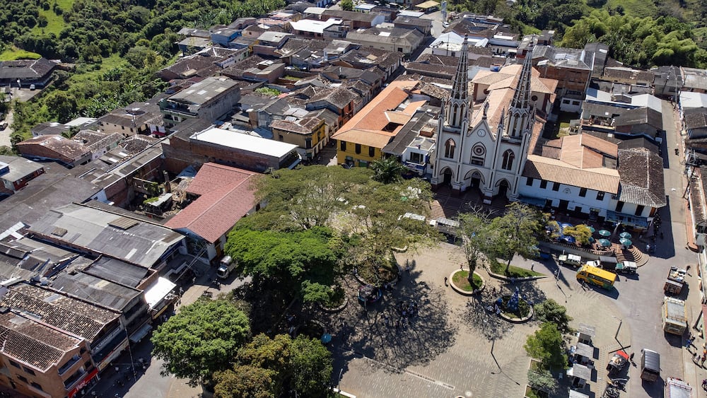 An aerial view of a town with a prominent church, a central plaza, and surrounding buildings.
