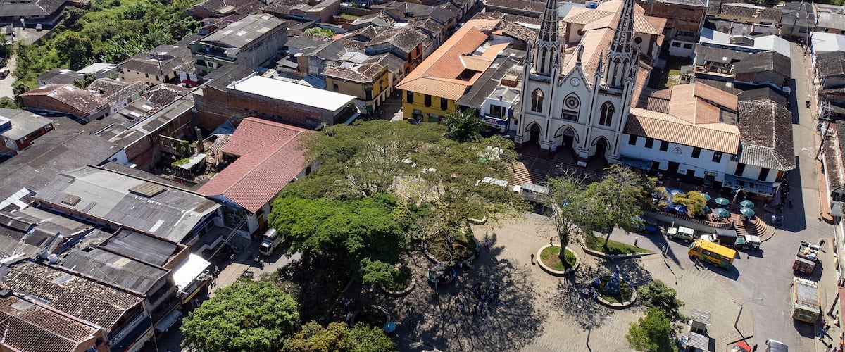 An aerial view of a town with a prominent church, a central plaza, and surrounding buildings.