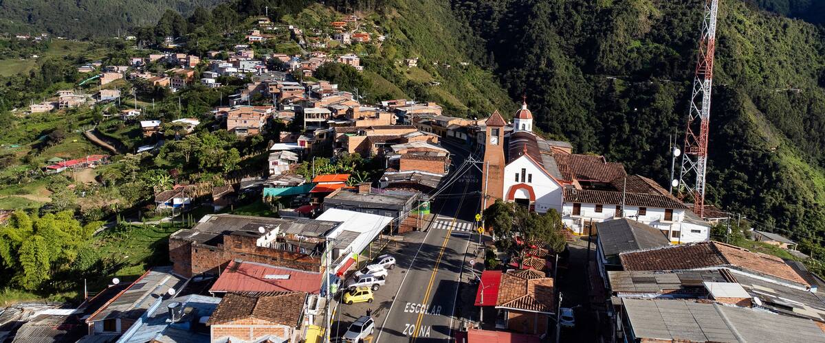A hillside village with a prominent church, a school, and a tall communication tower.