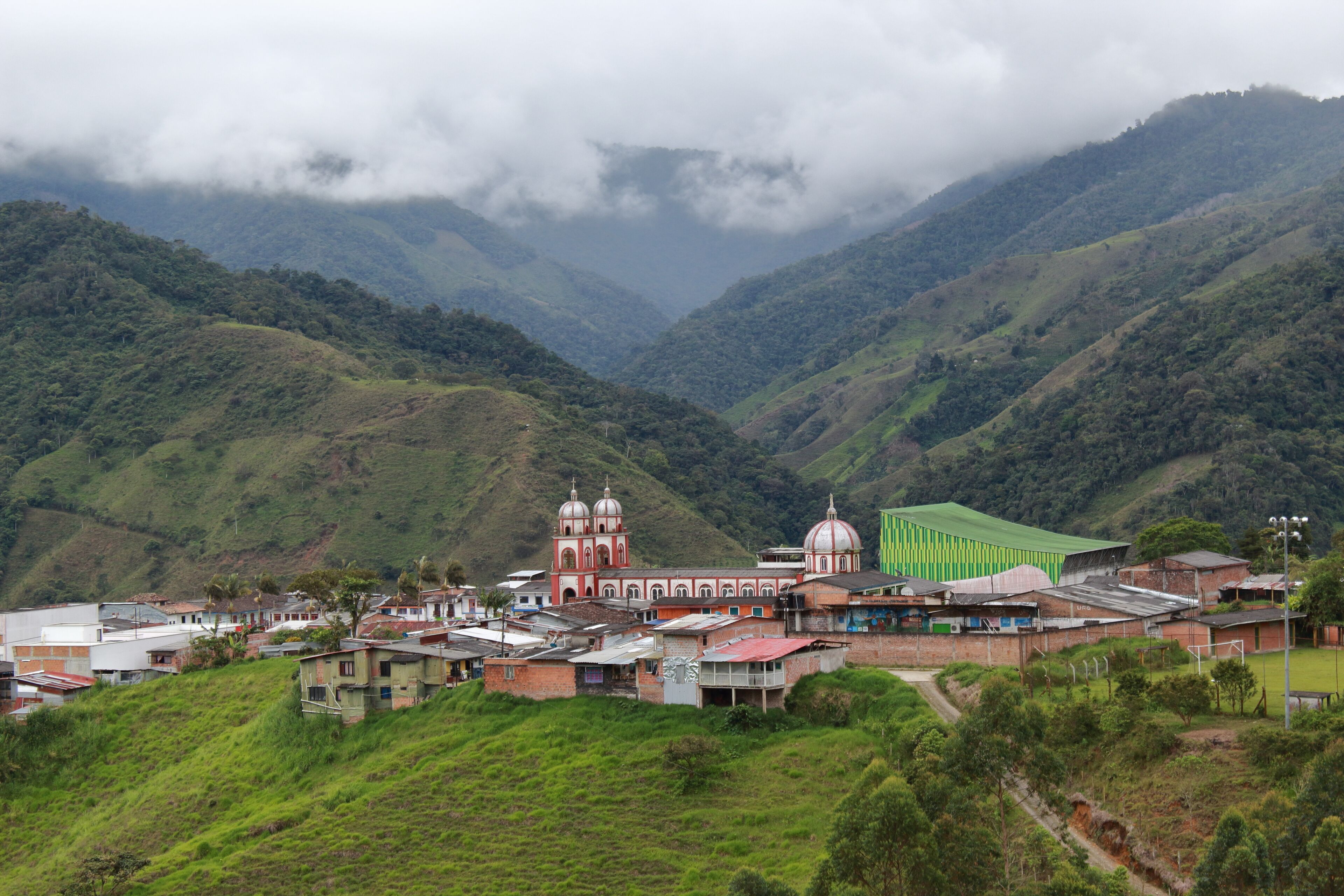 A valley with a church, a sports field, and lush green hills.