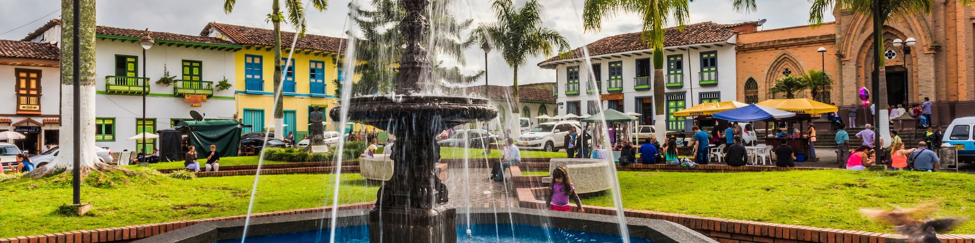 A fountain surrounded by colorful buildings and palm trees.