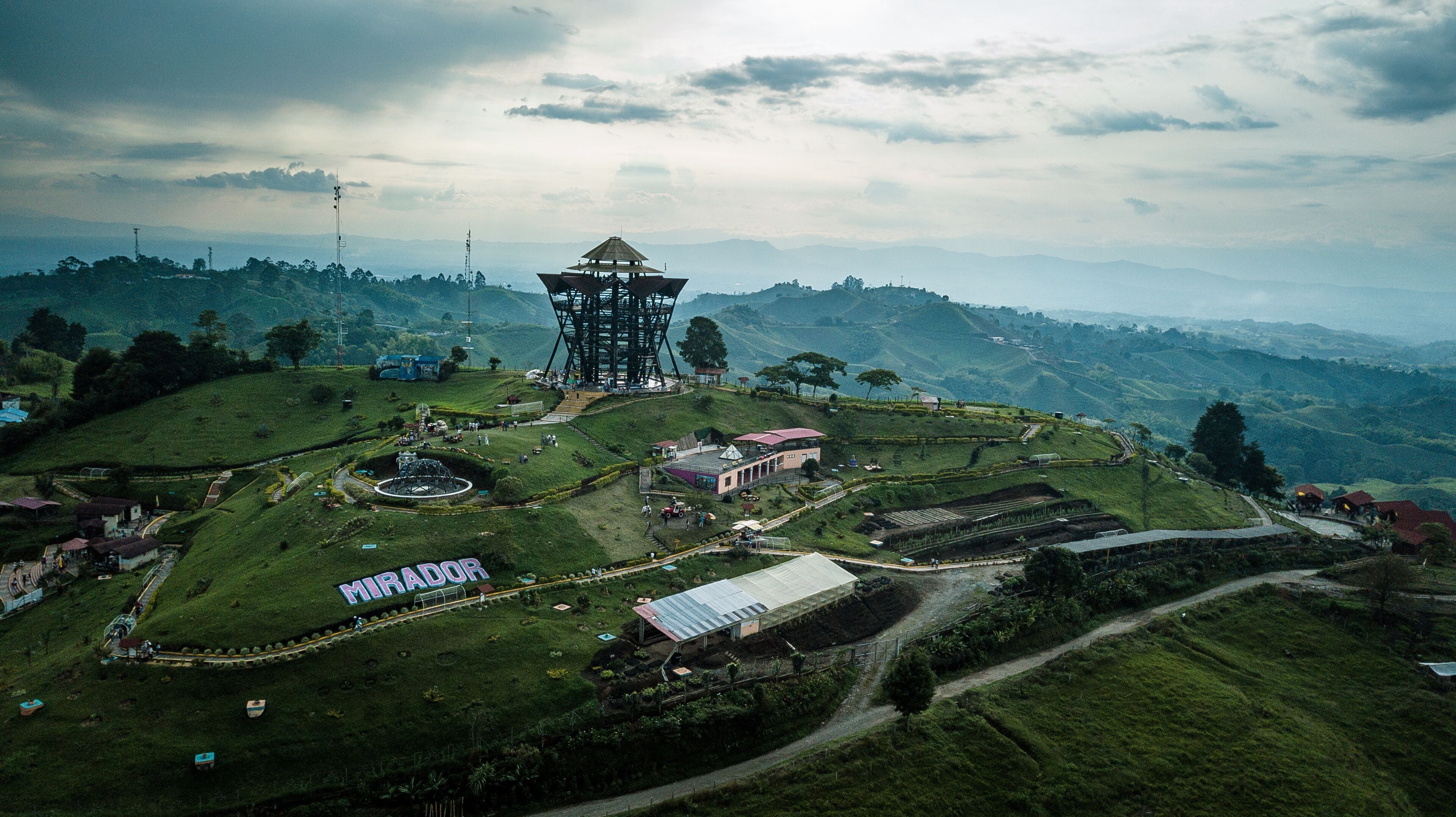 A large tower structure surrounded by lush green hills and a clear sky.