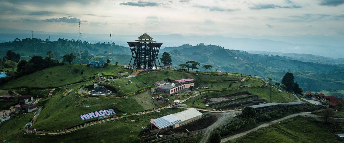 A large tower structure surrounded by lush green hills and a clear sky.