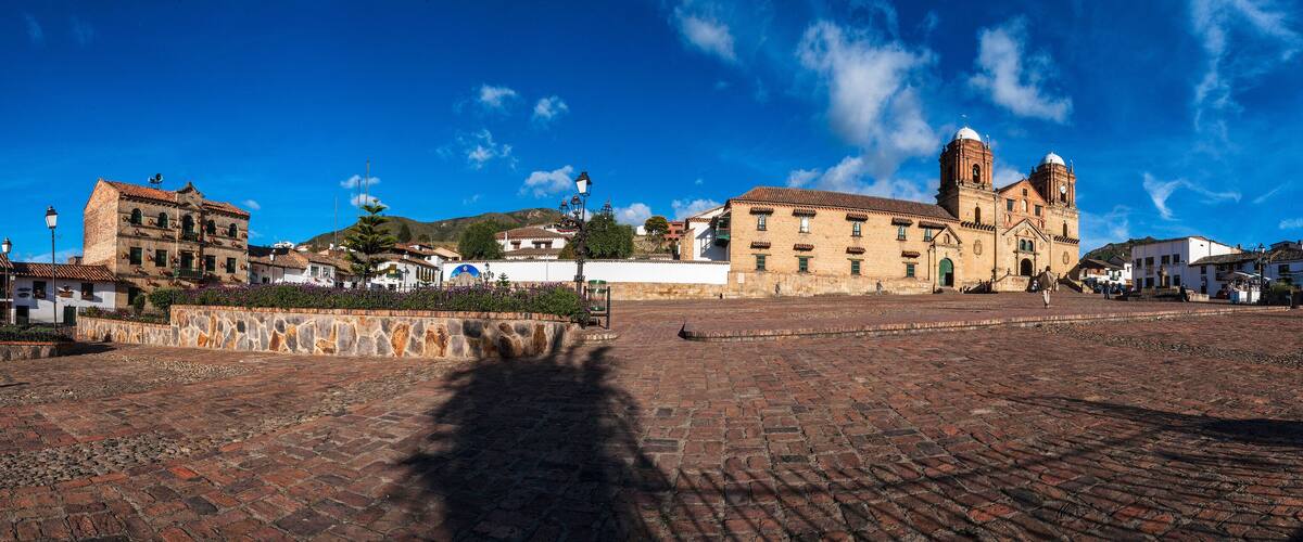 A historic plaza with cobblestone streets, a prominent church with two towers, and surrounding buildings.