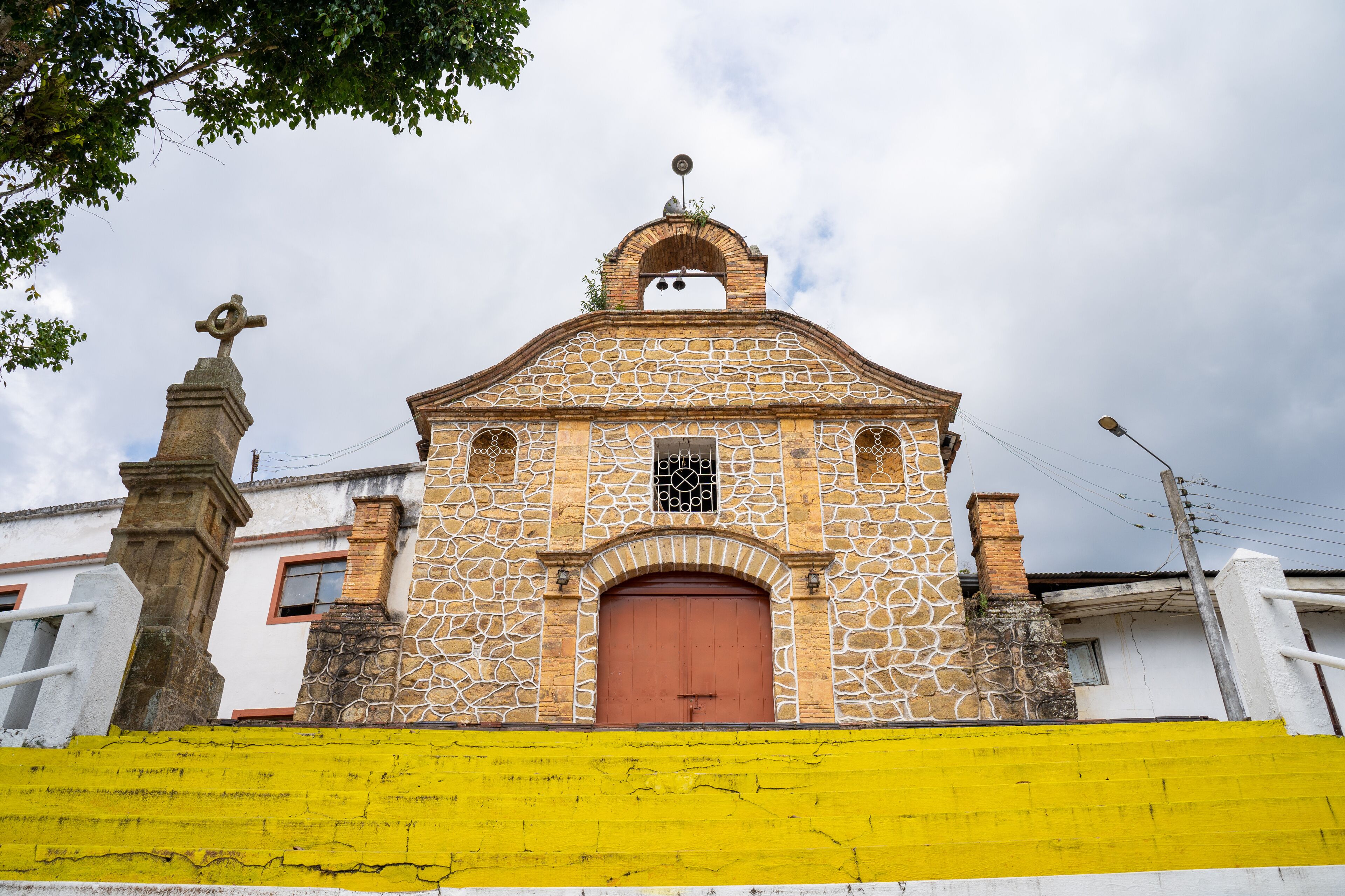 A church with a stone facade, a red door, and a cross on top.