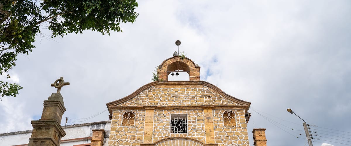 A church with a stone facade, a red door, and a cross on top.