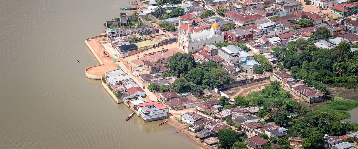 An aerial view of a riverside town with a prominent church and residential buildings.