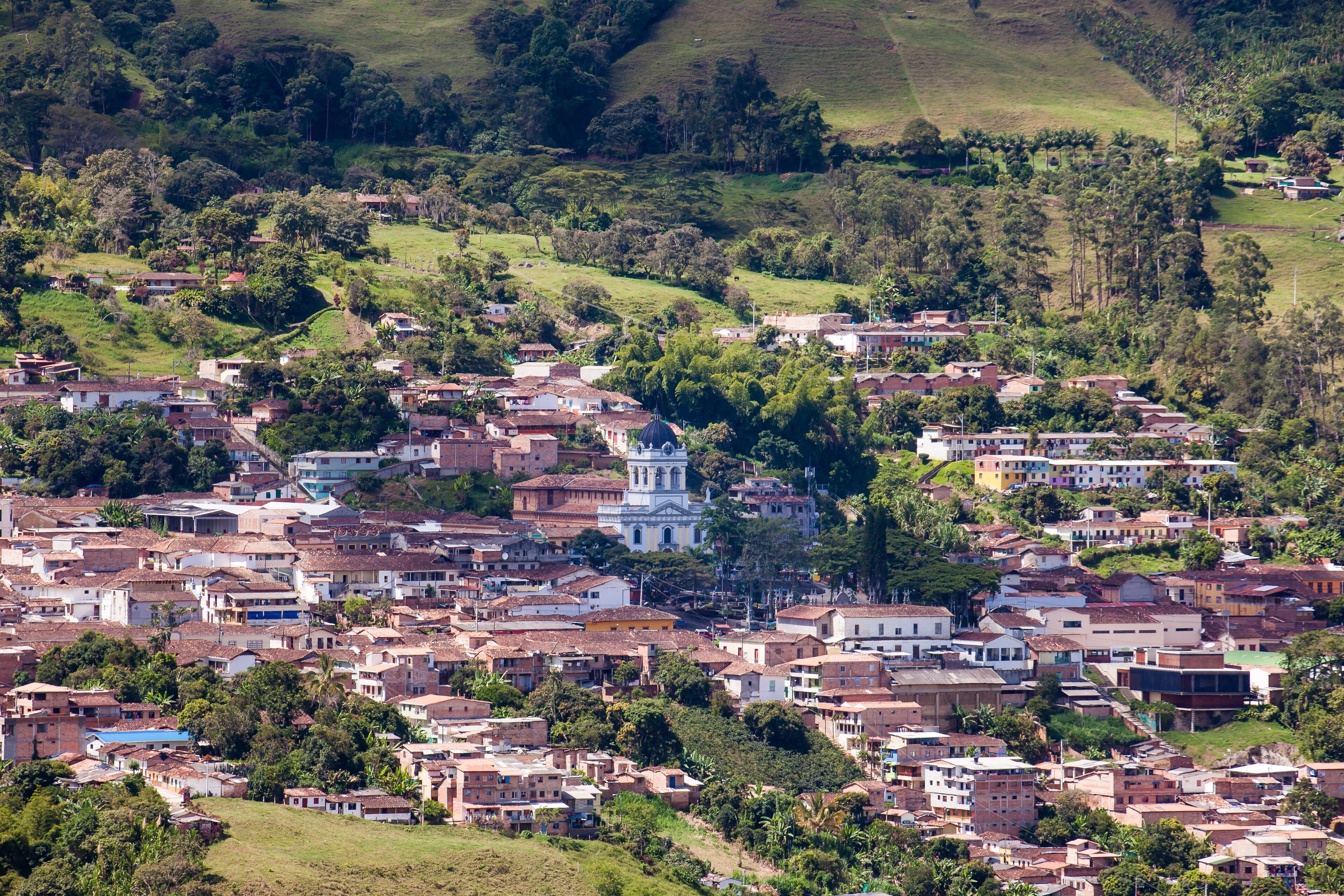 A densely populated hillside town with a prominent church and lush greenery.