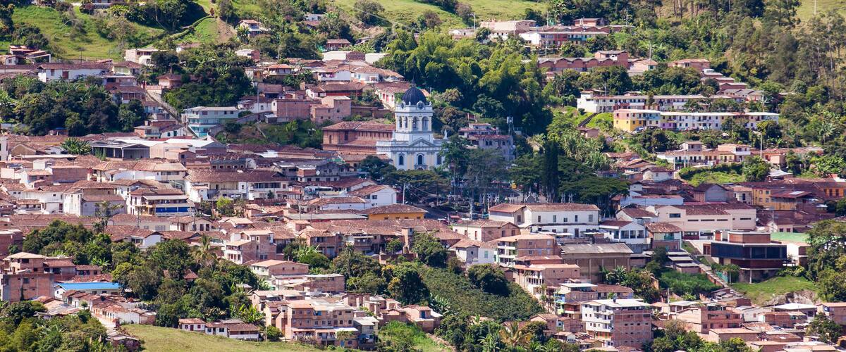 A densely populated hillside town with a prominent church and lush greenery.