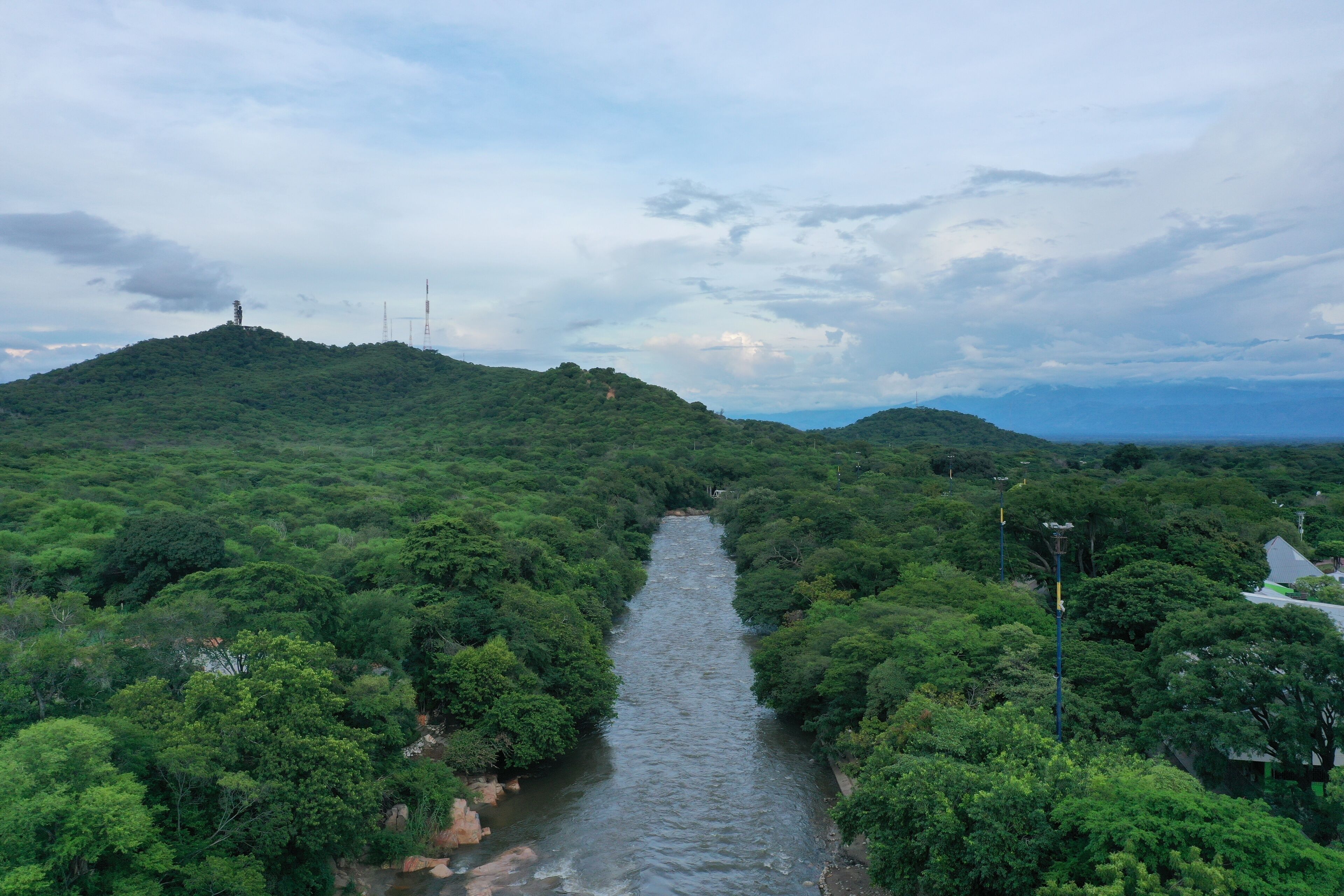 A river flowing through a dense forest with hills on either side.