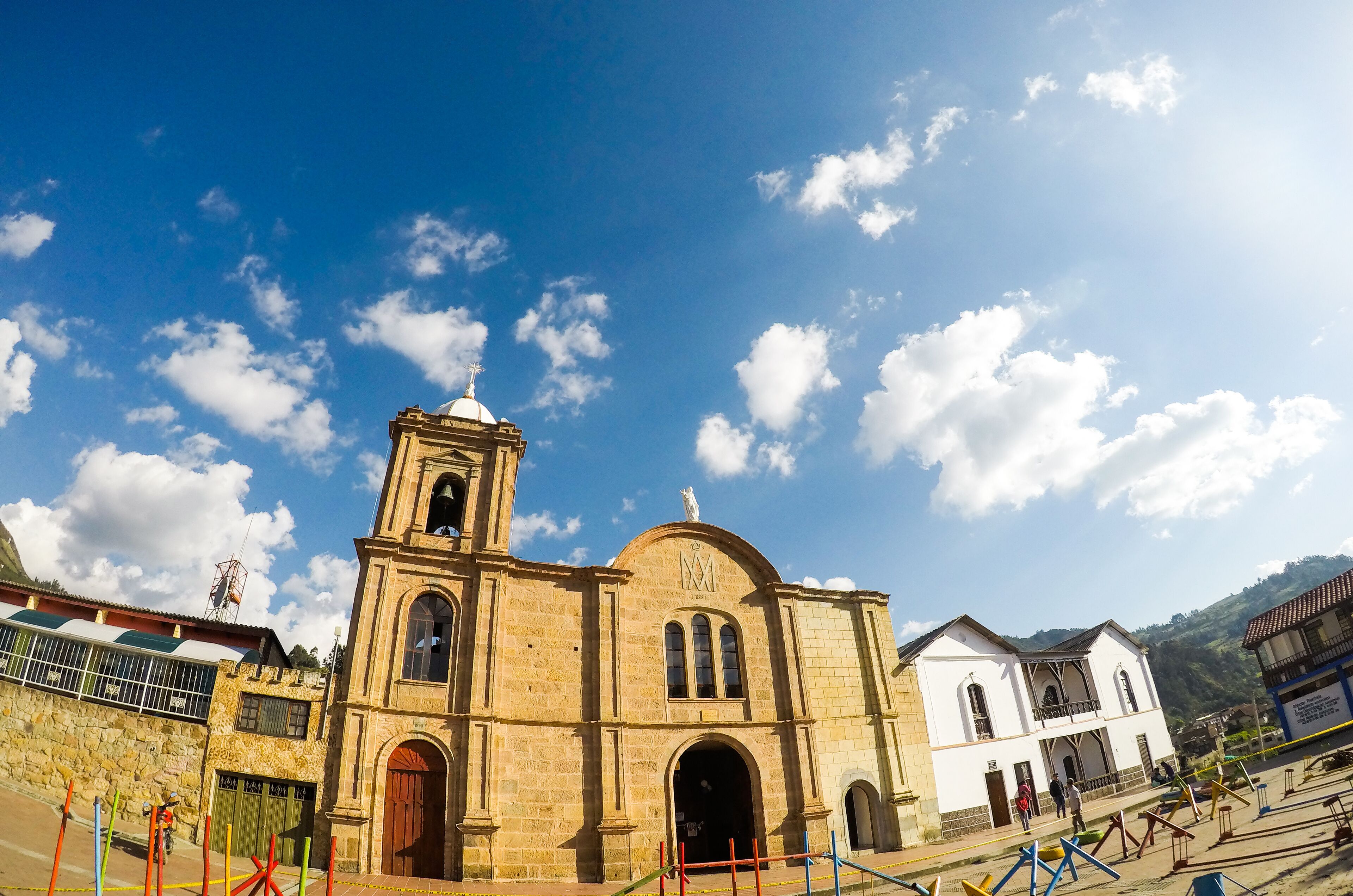 A historic church with a bell tower and arched windows, surrounded by a mountainous landscape.