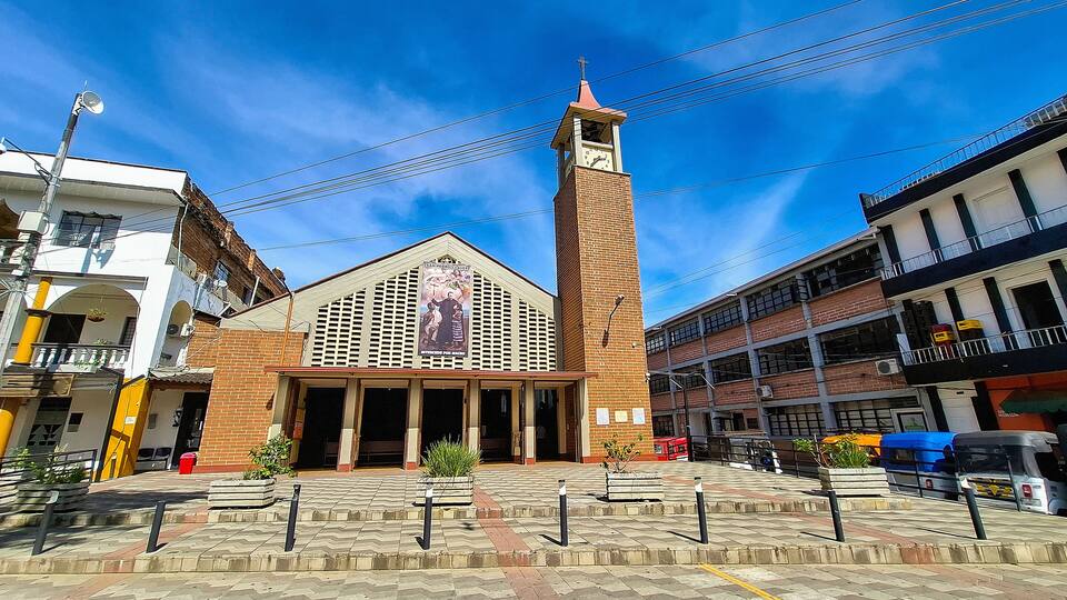 A church with a tall bell tower, a large clock, and a banner with religious figures.