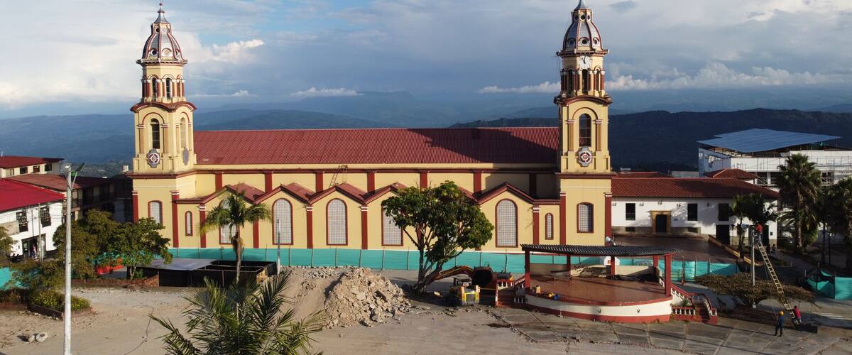A church with two towers and a red roof, surrounded by construction and palm trees.