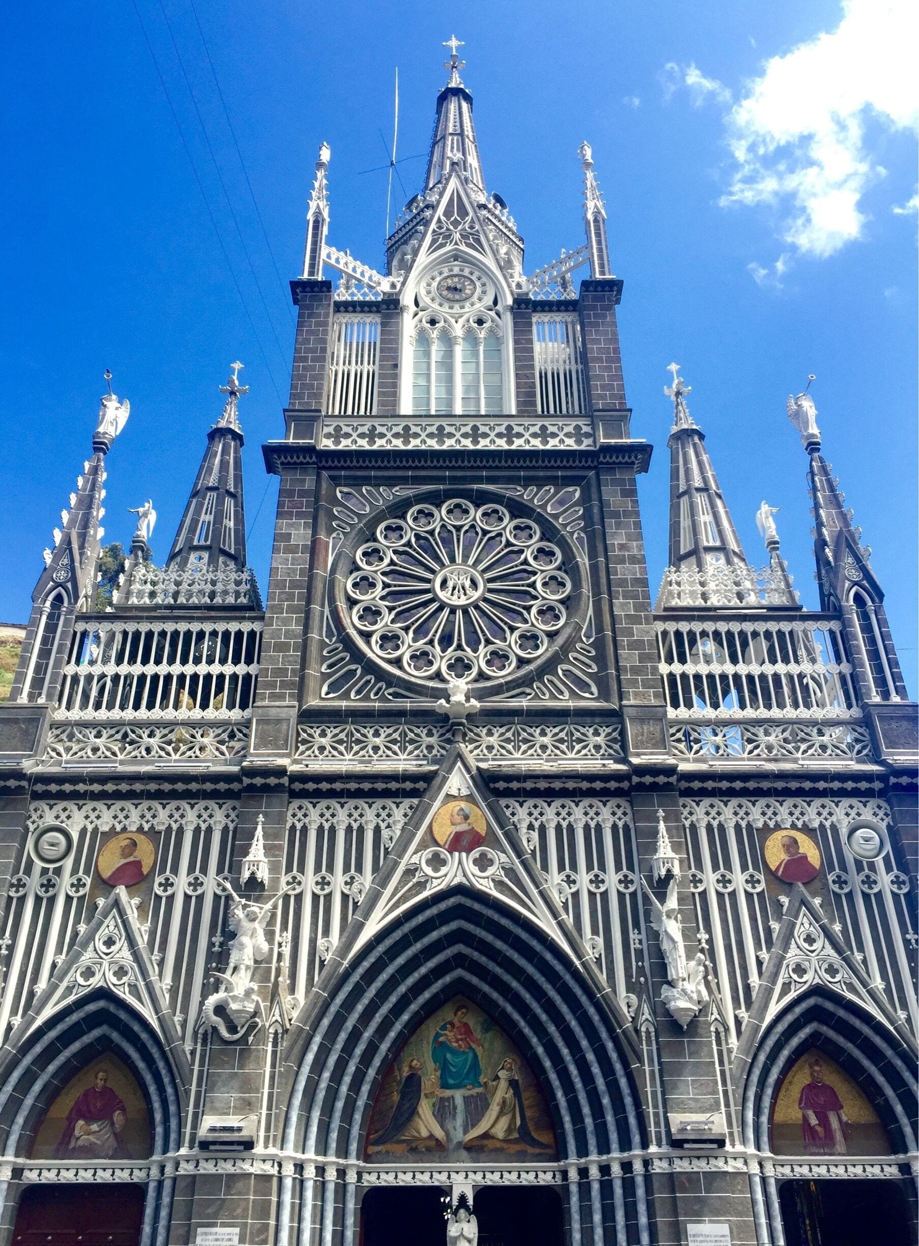A Gothic cathedral with intricate spires, a large rose window, and religious paintings.