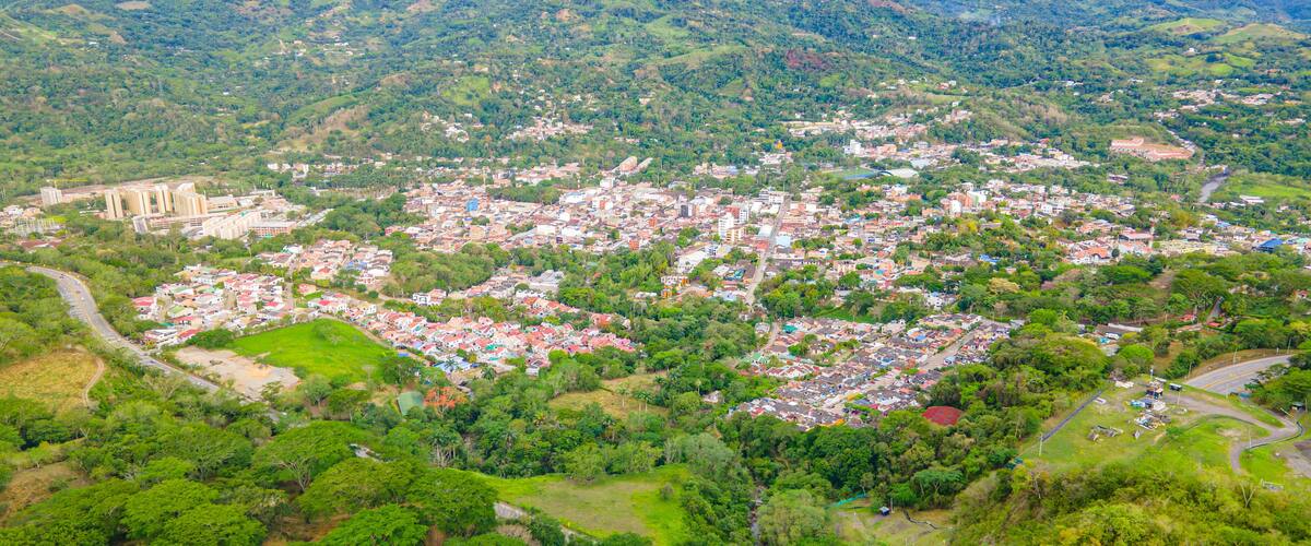 A densely populated town nestled in a mountainous region with lush greenery and a prominent church.