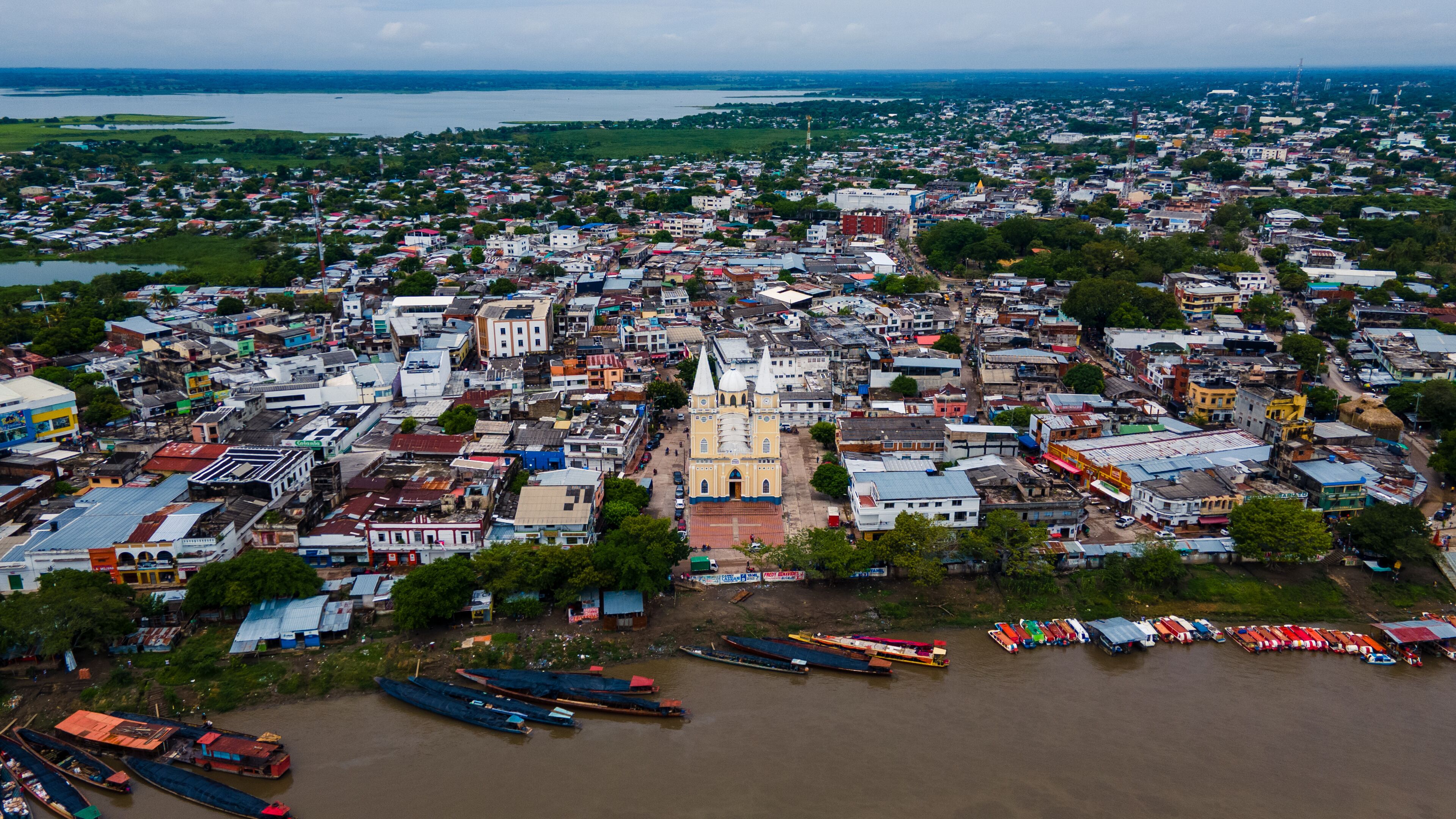 An aerial view of a city with a prominent church, dense housing, and a river with boats.