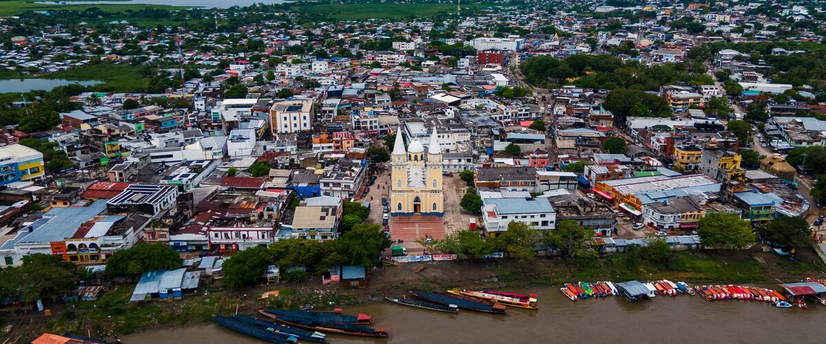 An aerial view of a city with a prominent church, dense housing, and a river with boats.