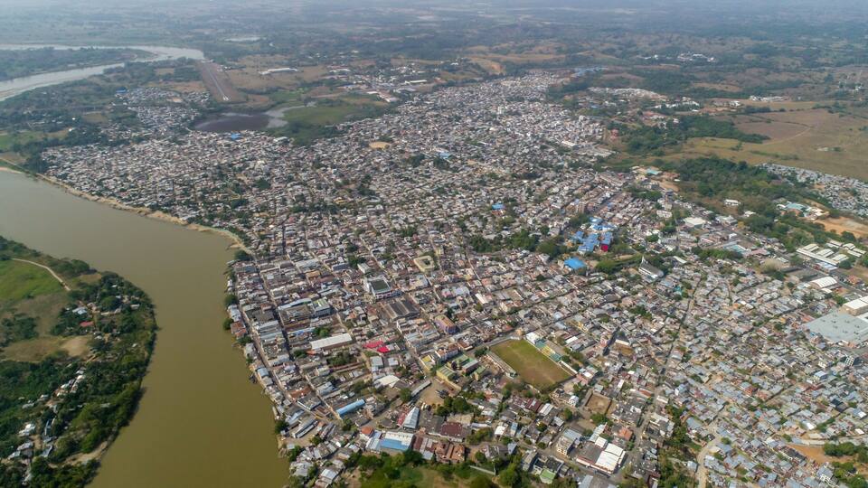 An aerial view of a densely populated urban area with a river on the left.
