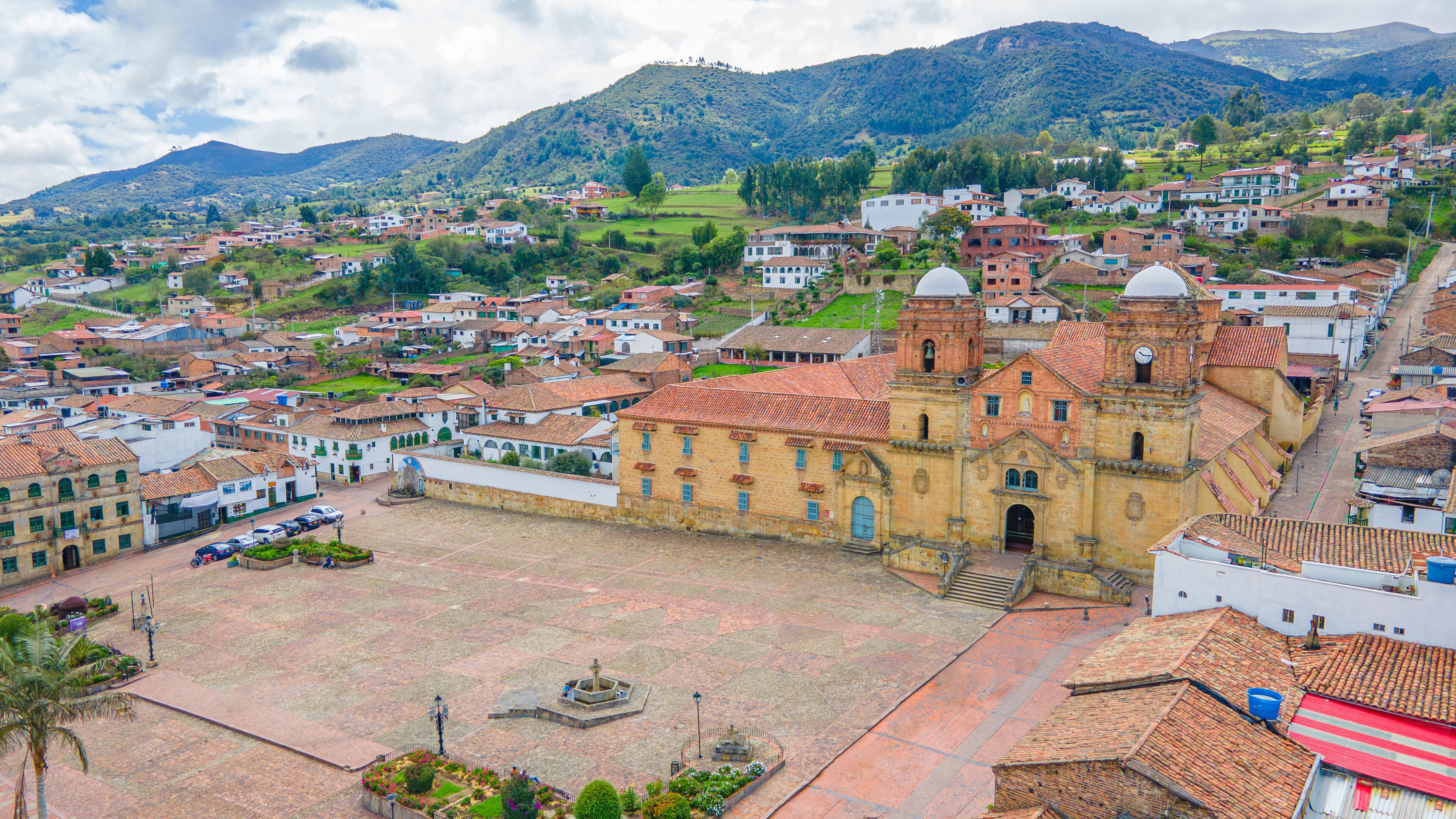 A town with a prominent church, a plaza, and surrounding residential areas with hills in the background.