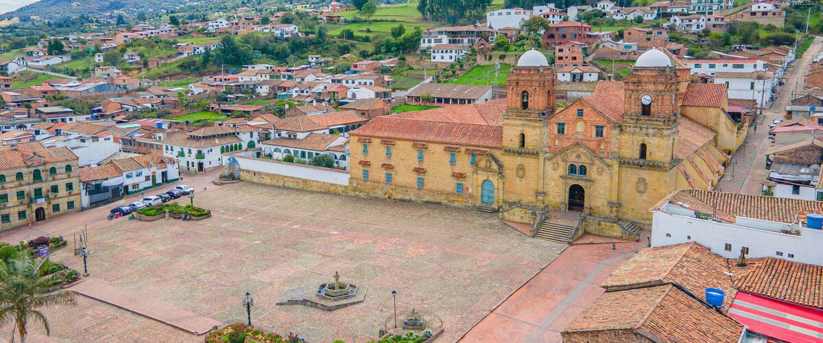 A town with a prominent church, a plaza, and surrounding residential areas with hills in the background.