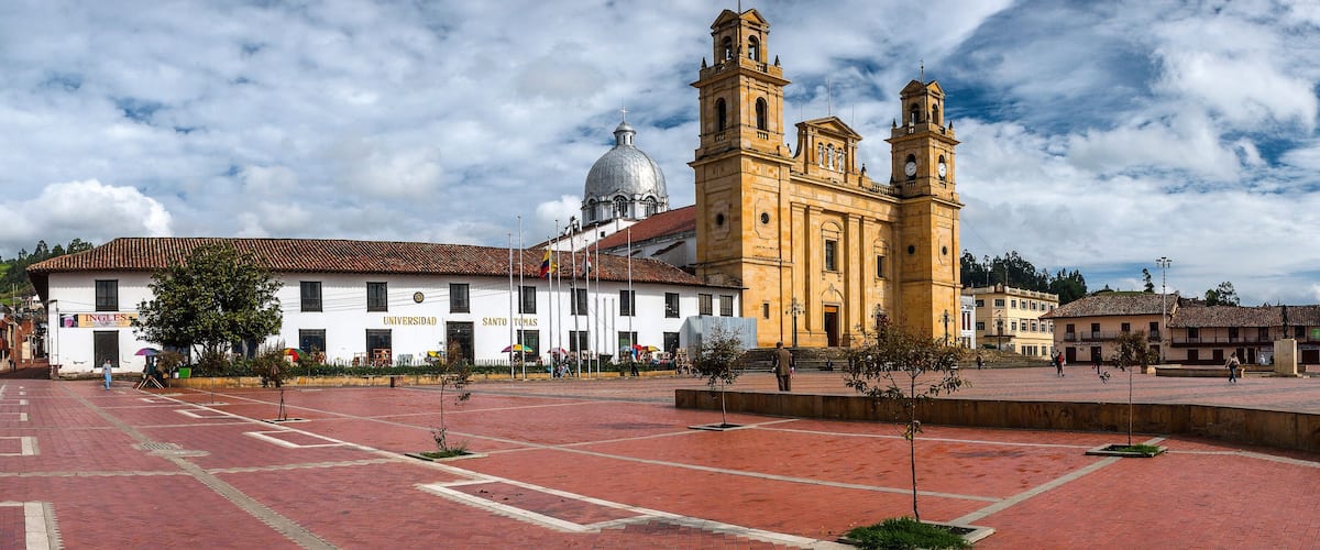 A plaza with a historic building featuring a prominent clock tower and a dome.