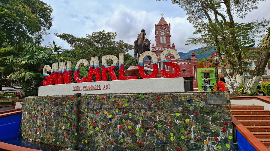 A colorful sign with 'MIGUEL GONZALEZ' and 'SOMOS PROVINCIA AB' in front of a church with a clock tower.