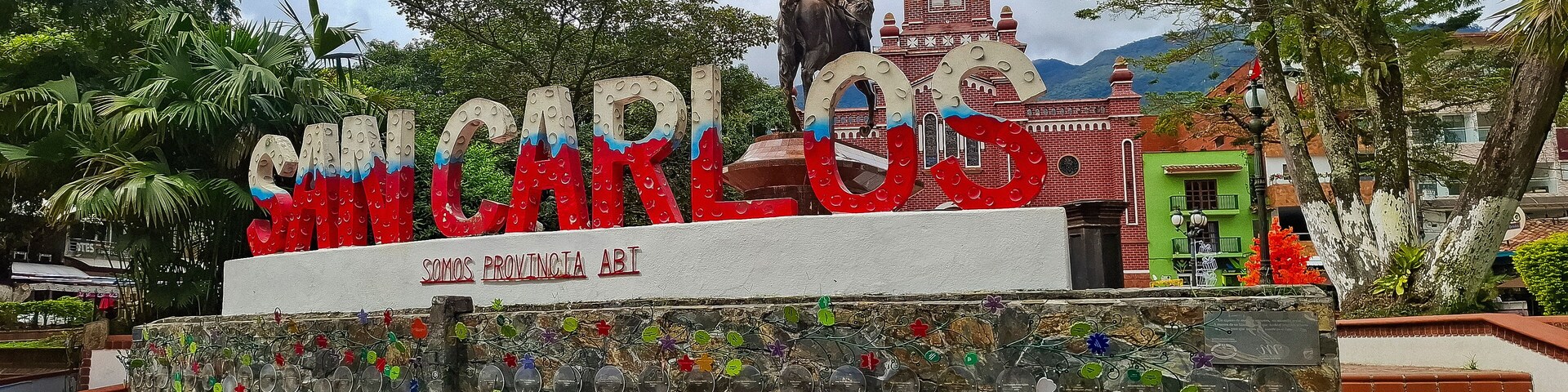 Un letrero colorido con 'MIGUEL GONZALEZ' y 'SOMOS PROVINCIA AB' frente a una iglesia con una torre del reloj.