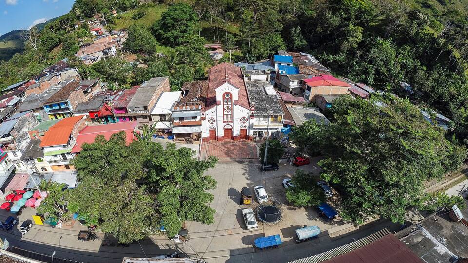A hillside town with a prominent church, colorful buildings, and lush greenery.