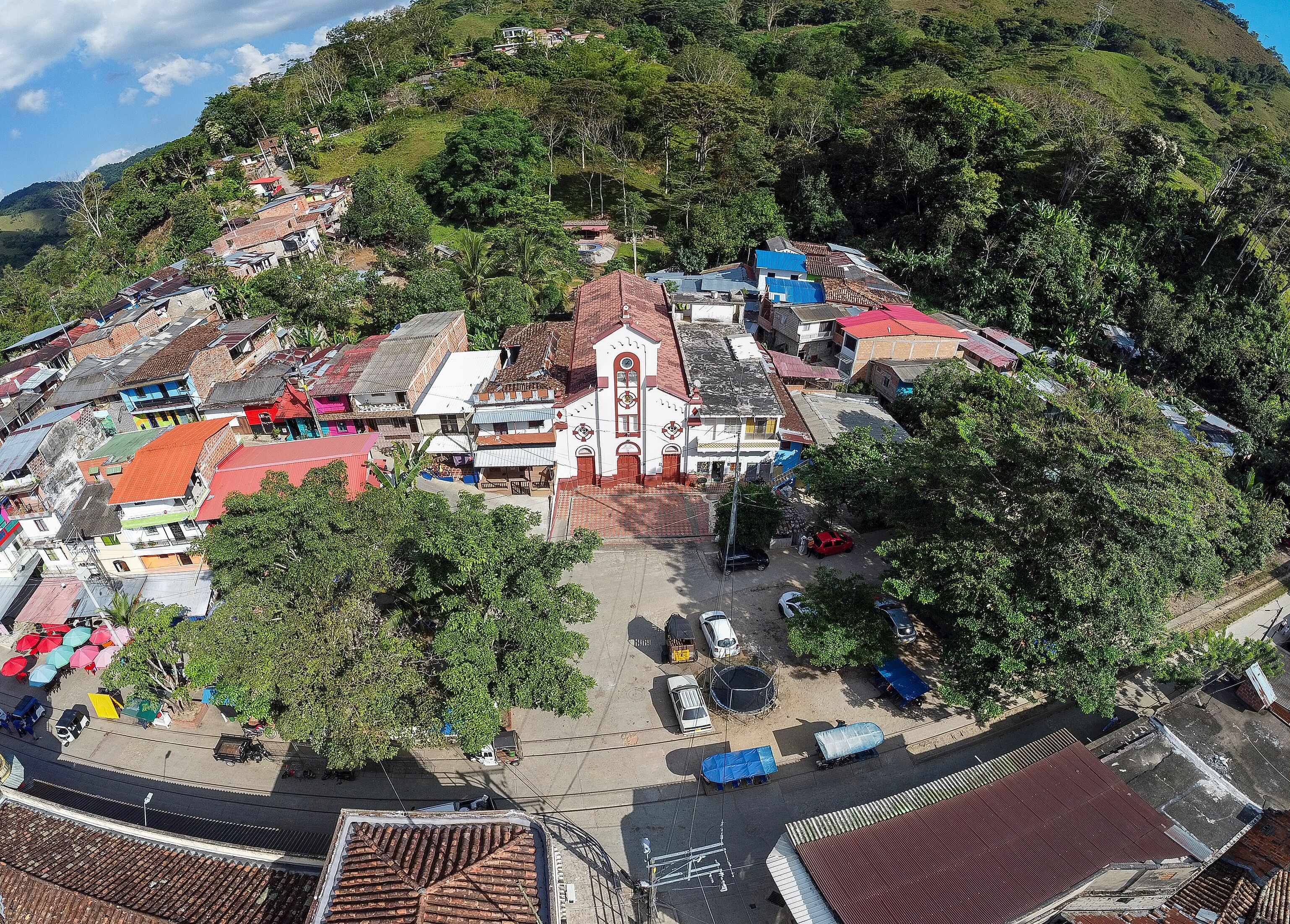 A hillside town with a prominent church, colorful buildings, and lush greenery.