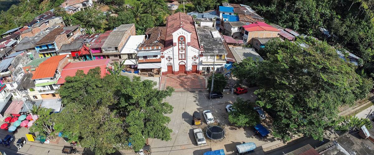 A hillside town with a prominent church, colorful buildings, and lush greenery.