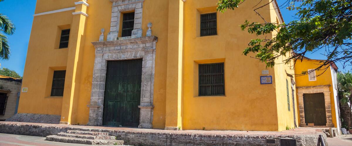 A yellow church with a bell tower and a stone entrance.