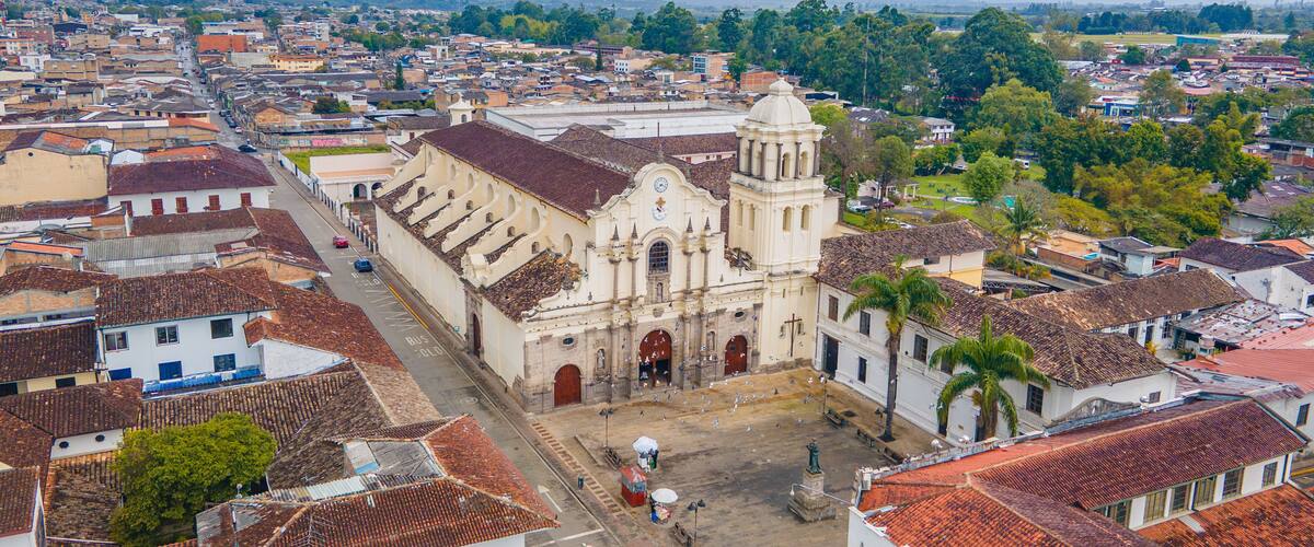A historic church with a dome and bell tower, surrounded by a cityscape with red-tiled roofs and greenery.
