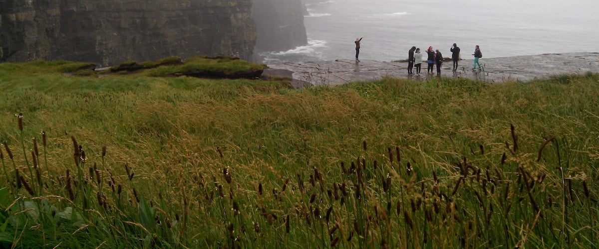 A coastal cliff with a group of people standing on the beach.