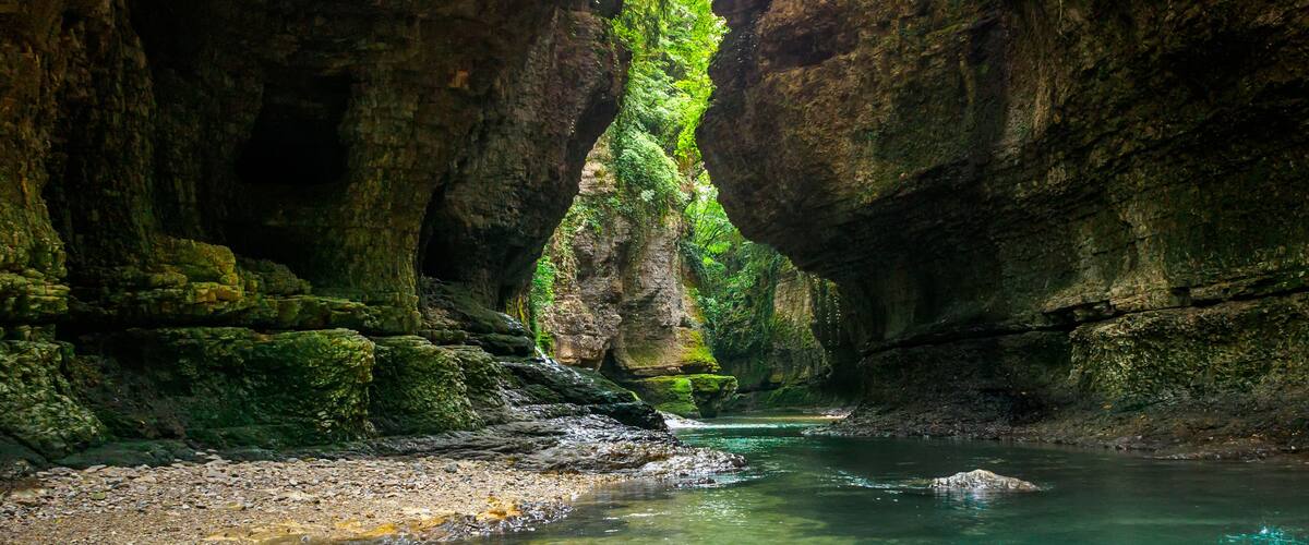 A clear turquoise river flowing through a rocky canyon with moss-covered walls.