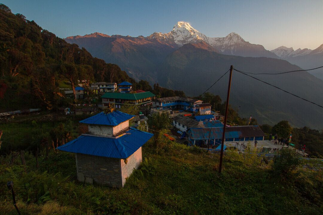A village with traditional houses and a snow-capped mountain in the background.