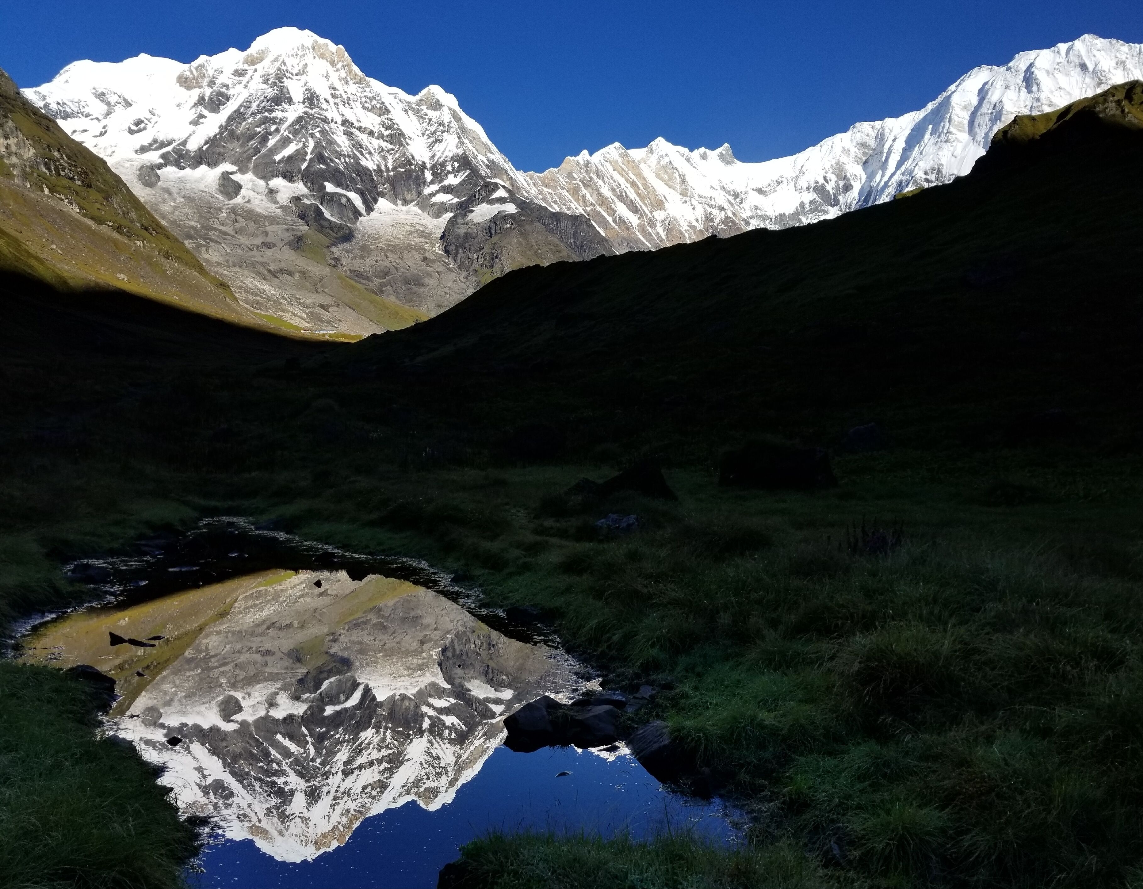A mountain range with snow-capped peaks and a clear blue sky.