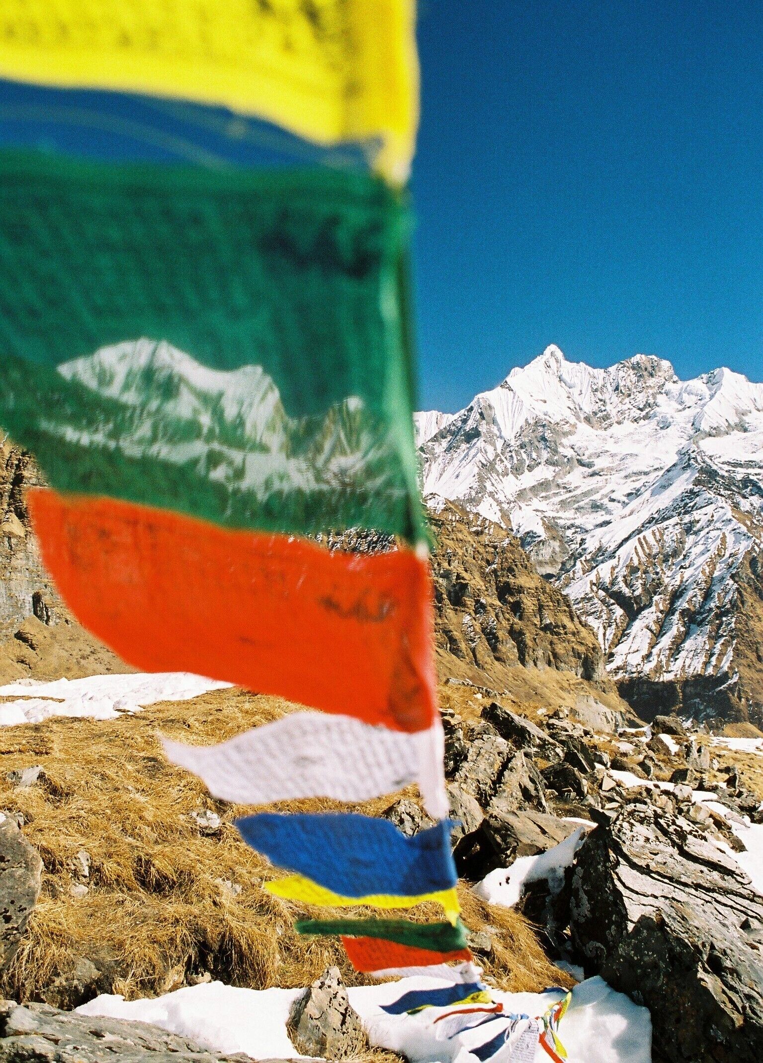 A prayer flag in front of a snow-capped mountain range.