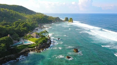 A coastal resort with clear turquoise waters, rocky outcrops, and lush greenery.
