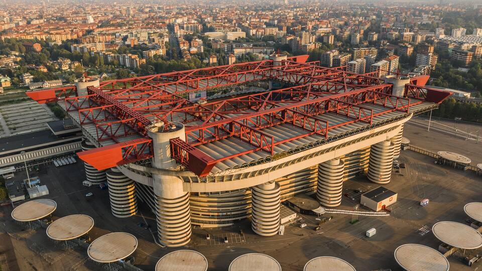A large industrial complex with multiple cylindrical storage tanks and a prominent red metal structure.
