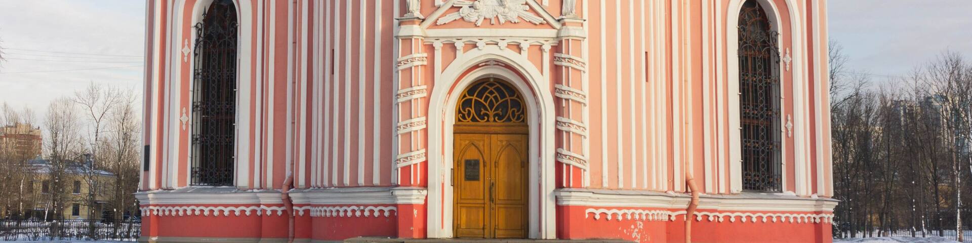 A pink and white church with a golden door and multiple spires.