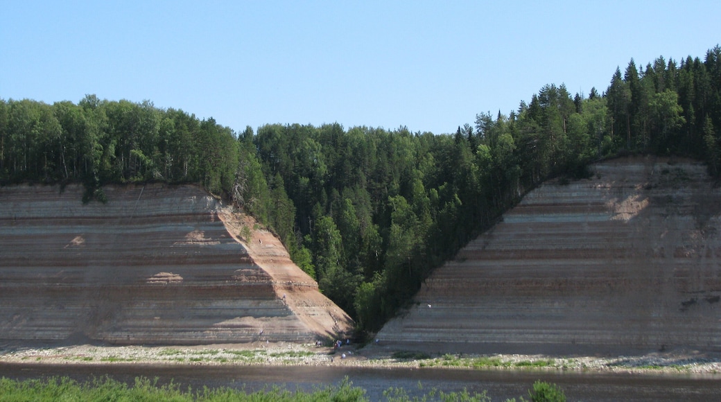 Sukhona is a flat river, originates in the Kubensky lake and flows quietly and calmly. But closer to its mouth (near Veliky Ustyug, the river flows into the Northern Dvina) suddenly its meek character changes into a steep mountain temper. Rolls and sills begin, the course changes abruptly several times, and the current accelerates to 5 m / s.
The village of Opokie (or the earlier name - Threshold) stands at the steepest bend and the most dangerous threshold. In the old days, when rivers were the main trade routes, merchants preferred not to take risks, but to drag vessels with goods of 800 m to be dragged.
It was here, under the onslaught of the river, that Sukhonsky rocks were formed. Gradually digging into the thickness of the ancient Permian and Quaternary sediments, the river exposed a 70-meter layer of red clay, and white gypsum, and other mineral rocks that are hundreds of millions of years old. And all this naked "construction" fascinates with its correct, and sometimes even ideal, geometric shapes and a restrained, but expressive palette. A dense northern forest is green on the cliffs.