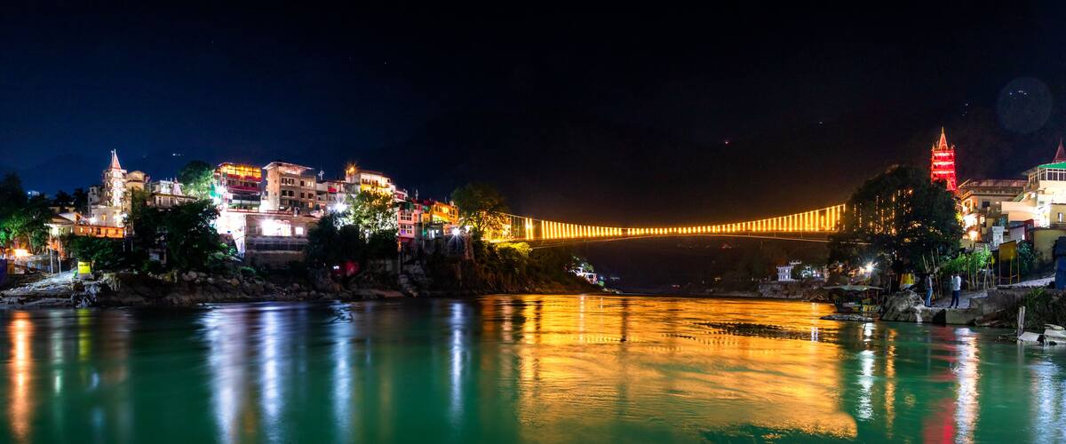 A river at night with a bridge and illuminated buildings on the opposite bank.